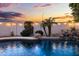 Beautifully landscaped pool area with a waterfall feature, lush greenery, and a tranquil ambiance under a colorful evening sky at 21630 N 30Th Ln, Phoenix, AZ 85027
