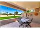 Covered patio area with seating and view of the green lawn and palm trees at 25261 S Berry Brook Dr, Sun Lakes, AZ 85248