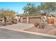 Tan home featuring a three-car garage, desert landscaping, and mature trees at 3138 W Ravina Ln, Anthem, AZ 85086