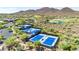 Aerial view of three well-maintained blue tennis courts surrounded by desert landscape and homes at 3138 W Ravina Ln, Anthem, AZ 85086