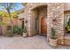 Close up of the stone entryway features a beautiful wooden door, sconces, and desert landscaping at 37170 N Granite Creek Ln, Carefree, AZ 85377