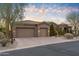 Exterior view of home with three-car garage, desert landscaping, and stone accents at sunset at 37170 N Granite Creek Ln, Carefree, AZ 85377