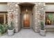 Inviting front entrance featuring a wood door, stone accents, and stylish sconces at 37170 N Granite Creek Ln, Carefree, AZ 85377