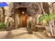 Home's welcoming front entrance showcases a stone facade, wooden door, and manicured landscaping at 37170 N Granite Creek Ln, Carefree, AZ 85377