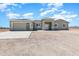 Exterior elevation of the beige single story home featuring a wide driveway and desert landscape at 40715 W Georgia Ave, Tonopah, AZ 85354