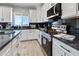 Modern kitchen boasts white cabinetry, black marble counters, and stainless steel appliances at 40715 W Georgia Ave, Tonopah, AZ 85354