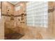 Luxurious walk-in shower with travertine tile, a built-in bench, and decorative glass block window for natural light at 41906 N Crooked Stick Rd, Anthem, AZ 85086