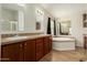 Bathroom showcasing double sinks, dark wood cabinets, and a luxurious soaking tub at 53040 W Whirly Bird Rd, Maricopa, AZ 85139