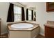 Bathroom featuring a large soaking tub with tile surround, next to a window for natural light at 53040 W Whirly Bird Rd, Maricopa, AZ 85139