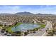 Expansive aerial view of a Primary-planned community with a picturesque lake, lush greenery, and stunning mountain views at 6121 S Ruby Dr, Chandler, AZ 85249