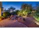 Beautifully landscaped backyard with a brick paver patio and illuminated trees at dusk at 13434 W El Sueno Ct, Sun City West, AZ 85375