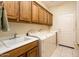 The laundry room is equipped with a sink, a washer, a dryer, and plenty of cabinet space at 13434 W El Sueno Ct, Sun City West, AZ 85375