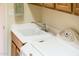 Bright laundry room with a utility sink, wood cabinets, white countertop, and a modern faucet at 13434 W El Sueno Ct, Sun City West, AZ 85375