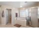 Bathroom featuring a soaking tub, glass enclosed shower and access to a private toilet room at 16918 W Statler St, Surprise, AZ 85388