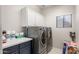 Efficient laundry room with modern washer and dryer, complemented by upper cabinets and counter space at 16918 W Statler St, Surprise, AZ 85388