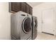 Laundry area featuring modern front load washer and dryer and dark cabinets at 17462 W Straight Arrow Ln, Surprise, AZ 85387
