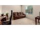 Comfortable living room features a leather sofa and a sunlit window at 17462 W Straight Arrow Ln, Surprise, AZ 85387