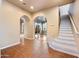 Open-concept living room featuring terracotta tile flooring, arched doorways, and a staircase at 2134 E Honeysuckle Pl, Chandler, AZ 85286