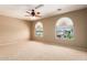Sunlit bedroom with neutral walls, plush carpet, a ceiling fan, and two arched windows at 2453 E Ebony Dr, Chandler, AZ 85286