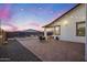 Backyard view featuring a paver patio, lush grass, and colorful sky at dusk at 25658 N 140Th Ln, Surprise, AZ 85387