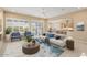 Staged living room featuring tile flooring, large windows with blinds, and modern furniture with a view of the kitchen at 26616 W Quail Ave, Buckeye, AZ 85396