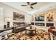 Cozy living room with a ceiling fan, comfortable seating, a stylish fireplace, and a large TV at 26828 W Piute Ave, Buckeye, AZ 85396