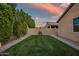 Landscaped backyard featuring lush green lawn, bordering trees and a brick perimeter at 3010 W Laredo Ln, Phoenix, AZ 85085