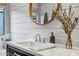 Modern bathroom sink featuring shiplap wall design, a round mirror, and decor accents at 3010 W Laredo Ln, Phoenix, AZ 85085