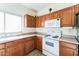 Bright kitchen featuring wooden cabinets, white appliances, and tile backsplash at 44922 W Alamendras St, Maricopa, AZ 85139
