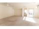 Open-concept living room with neutral carpet, a ceiling fan, and sliding glass door to the backyard at 44922 W Alamendras St, Maricopa, AZ 85139