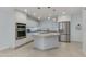 Modern kitchen featuring stainless steel appliances, a center island with cooktop, and sleek white cabinetry at 5333 N Las Casitas Pl, Phoenix, AZ 85016