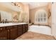 Bright bathroom featuring a soaking tub, a dual sink vanity, and decorative tile accents at 5523 W Yearling Rd, Phoenix, AZ 85083