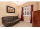 A serene living room featuring a leather sofa, a window with shutters, and warm neutral paint at 5523 W Yearling Rd, Phoenix, AZ 85083