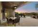 Covered back patio with a dining area overlooking the pool, lush landscaping, and sunset sky at 5892 E Evening Glow Dr, Scottsdale, AZ 85266