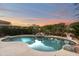 Backyard pool with a small waterfall feature, surrounded by lush desert landscaping at 5892 E Evening Glow Dr, Scottsdale, AZ 85266