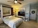 Cozy bedroom with a murphy bed, bright lighting, a TV, and access to the front door at 6161 S Pinehurst Dr, Chandler, AZ 85249