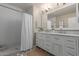 Stylish bathroom featuring double sinks, a large mirror, white subway tile, and a walk in shower at 6576 W Lone Cactus Dr, Glendale, AZ 85308
