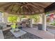 Outdoor kitchen featuring a grill, beverage cooler, and comfortable seating within a covered gazebo at 6576 W Lone Cactus Dr, Glendale, AZ 85308