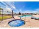 Community pool area with a hot tub, lounge chairs, fencing, and palm trees under a sunny sky at 7006 E Jensen St # 33, Mesa, AZ 85207