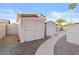 Backyard featuring storage sheds surrounded by gravel, landscaping, and a concrete walkway at 7538 E Forge Ave, Mesa, AZ 85208
