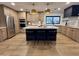 Modern kitchen featuring wood cabinets, stainless steel appliances, marble countertops, and a blue kitchen island at 7624 E Charter Oak Rd, Scottsdale, AZ 85260