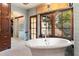 A lavish bathroom featuring a soaking tub, chandelier and dark wood trim at 8306 N Merion Way, Paradise Valley, AZ 85253