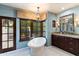 A luxurious bathroom featuring a soaking tub under a window and chandelier lighting at 8306 N Merion Way, Paradise Valley, AZ 85253