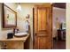 Charming bathroom featuring a wooden vanity, unique sink, decorative mirror, and an adjacent wooden door at 8306 N Merion Way, Paradise Valley, AZ 85253