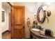 Elegant bathroom with a marble vanity, decorative mirror, sconce lighting, and an adjacent wooden door at 8306 N Merion Way, Paradise Valley, AZ 85253