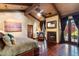 Cozy bedroom featuring wood floors, a fireplace, sitting area, and large windows overlooking the garden at 8306 N Merion Way, Paradise Valley, AZ 85253
