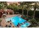 Aerial view of backyard pool with lounge chairs, a fire pit, mature trees, and a covered patio at 8306 N Merion Way, Paradise Valley, AZ 85253