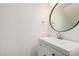 A clean and modern powder room with a stylish sink and round mirror at 8532 E Belleview St, Scottsdale, AZ 85257