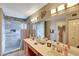 Well-lit bathroom with double sink vanity, large mirror, and walk-in shower featuring elegant tiling at 15237 N 61St Dr, Glendale, AZ 85306
