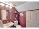 Charming half bathroom with pedestal sink, decorative shelves, and stylish purple paint at 15237 N 61St Dr, Glendale, AZ 85306